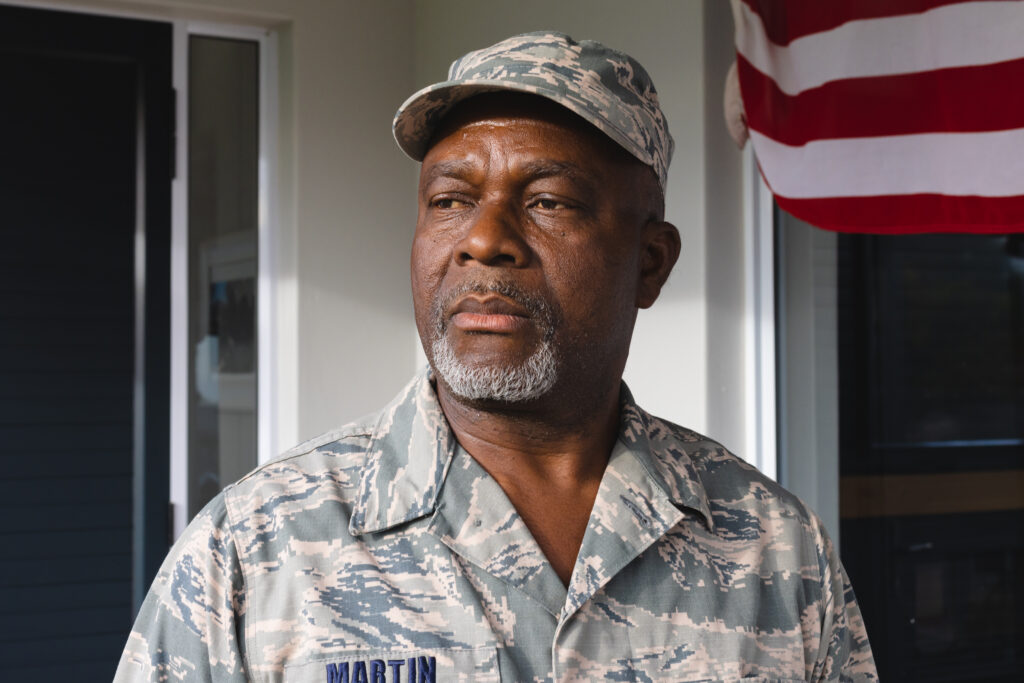 African american military senior man in camouflage clothing and cap looking away against house. Contemplation, unaltered, pride, military, armed forces, patriotism and homecoming concept.