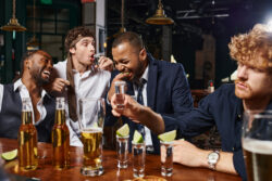 candid photo of funny and drunk men in formal wear binge drinking tequila on the weekend