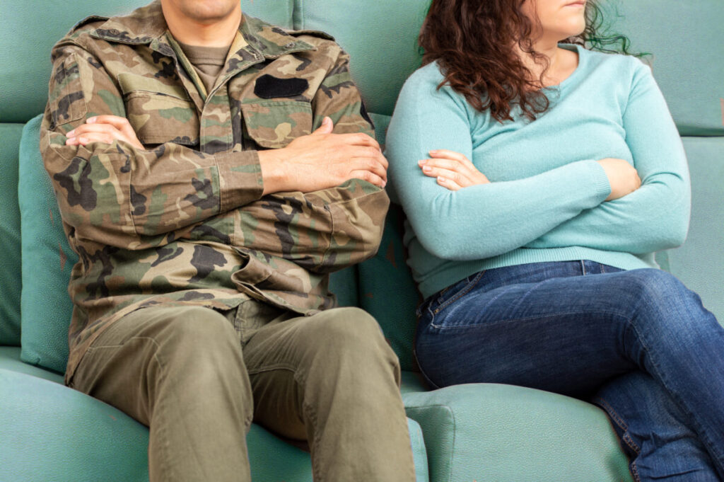 Cropped shot of a soldier and his unrecognizable wife sitting on the couch with their arms crossed after an argument
