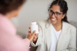 Jar with medication in therapist woman hand. Friendly lady showing her client medication drug pills, recommending supplement for mental health