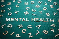 Mental health word from wooden letters. Mental health text on green background with many other letters